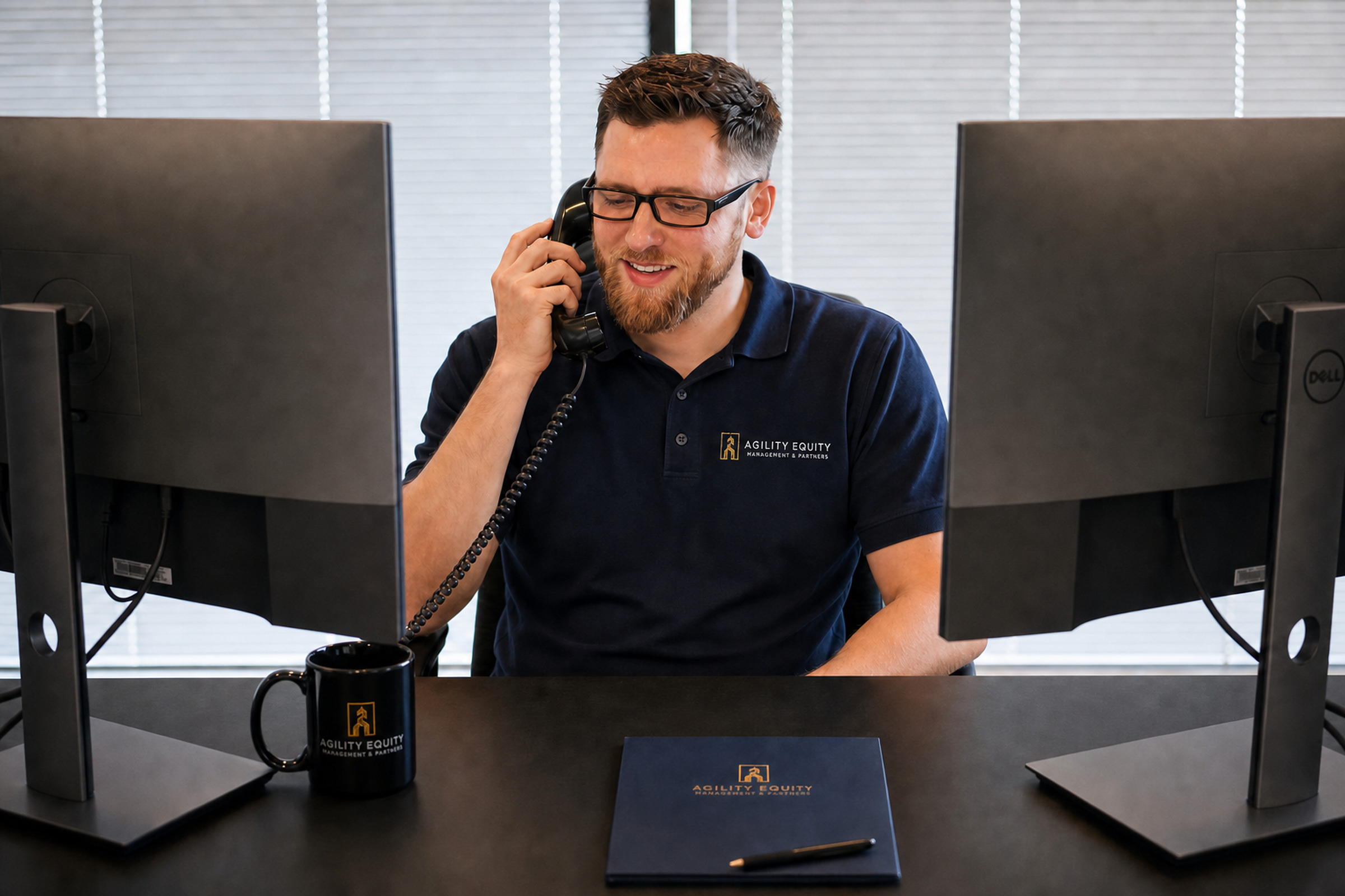 Agility Equity team member on the phone at a desk with a branded mug and notepad