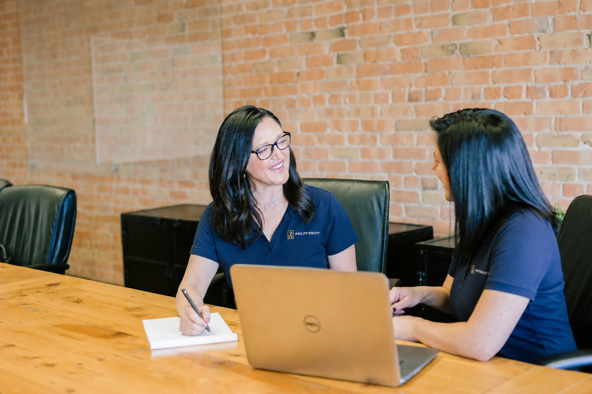 Agility Equity team members in branded polos discussing questions at a conference table