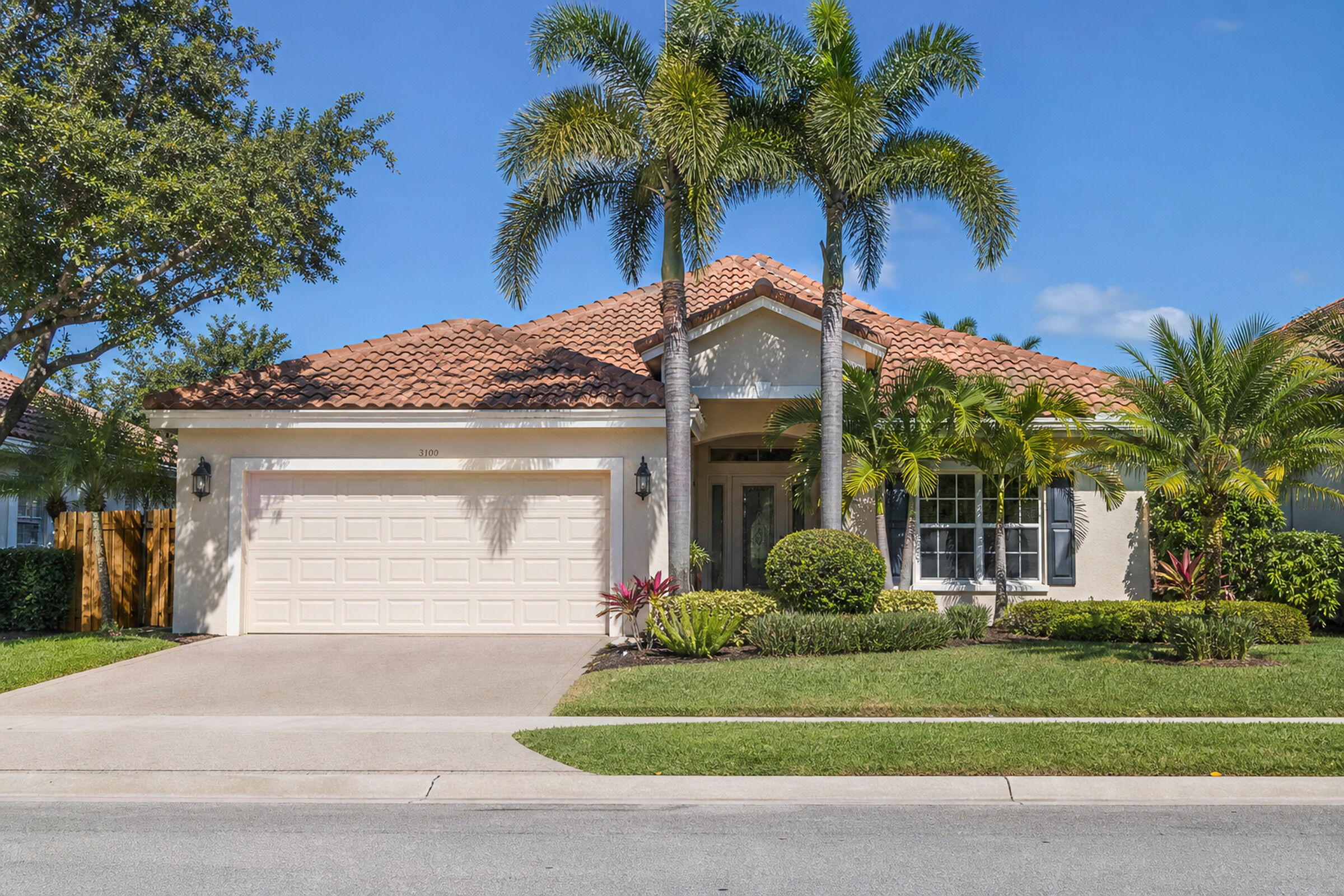 Average South Florida single-family stucco home with a tile roof and palm trees