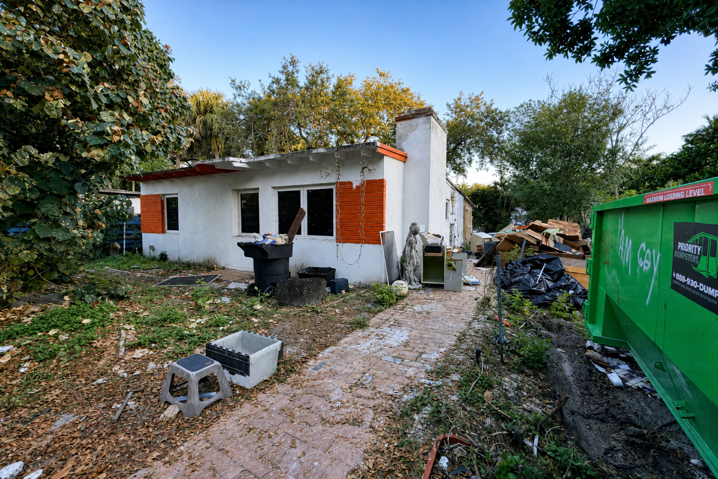 Neglected South Florida home with debris, trash, and a dumpster suggesting code violations