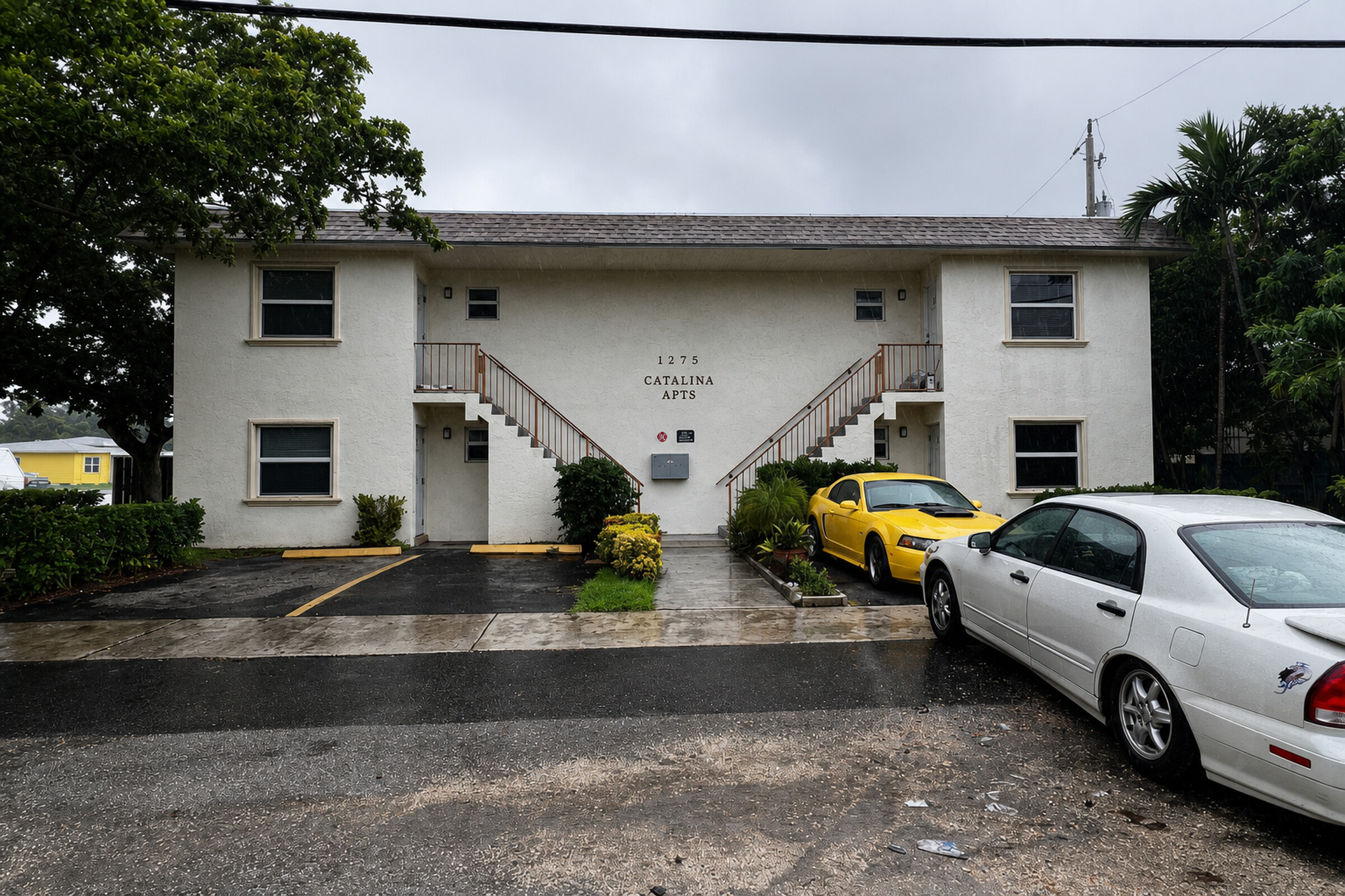 Two-story South Florida apartment building with cars parked out front on a rainy day